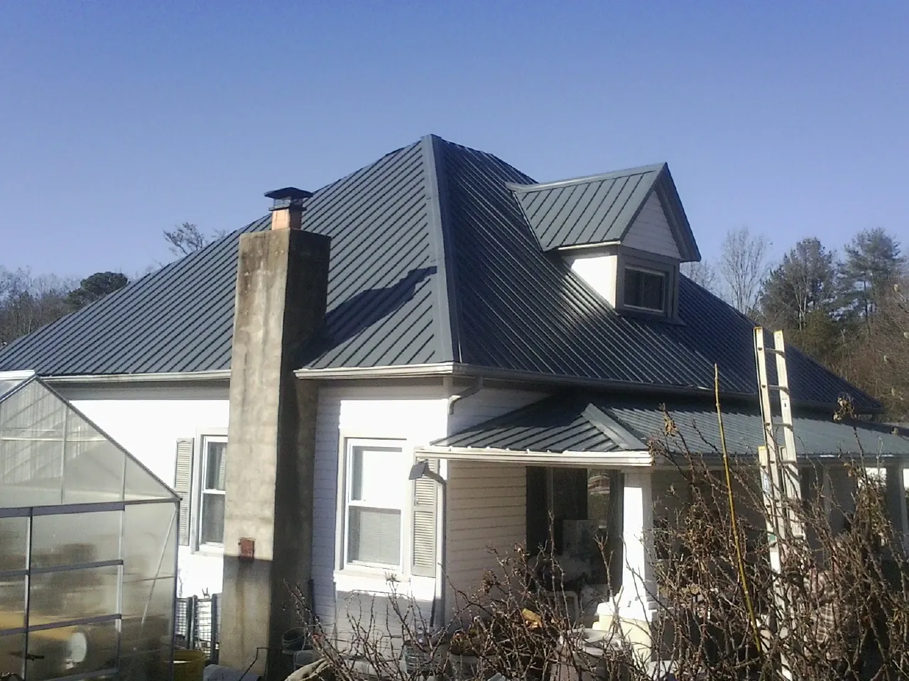Dark blue standing seam metal roof on a white farmhouse with dormer — Slate & Tile Roof Repair by Roofing Brothers in Hornbrook