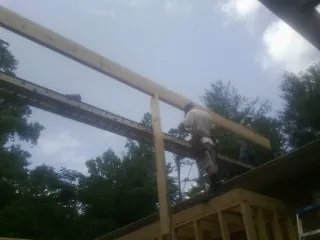 Carpenter setting a ridge beam over a new addition frame — Ice Dam Removal by Roofing Brothers in Hornbrook
