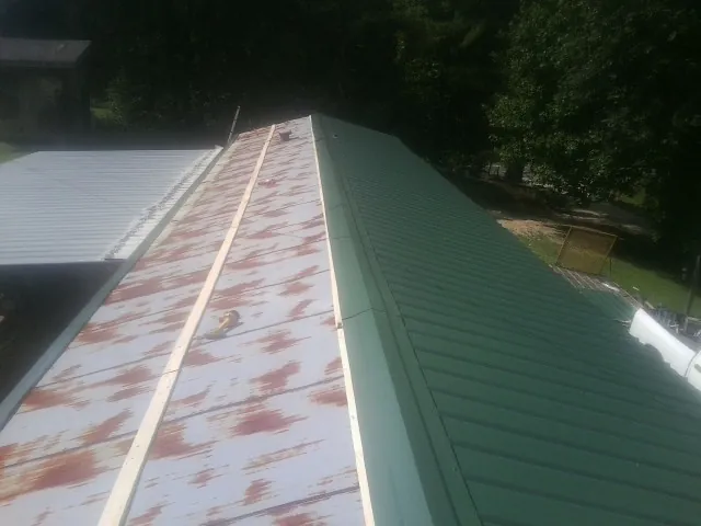Old rusted panels beside newly installed green metal roofing — Wind Damage Roof Repair by Roofing Brothers in Hornbrook