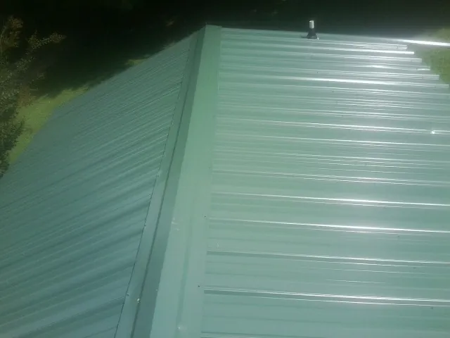 New green metal panels meeting at the ridge of a roof — Flat Roof Repair work by our crew in Hornbrook