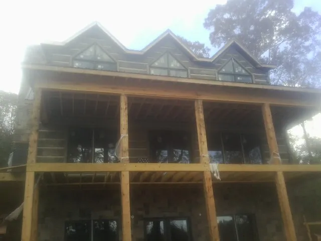 Dormers and porch framing on a large log home under construction — Roof Coating work by our crew in Hornbrook