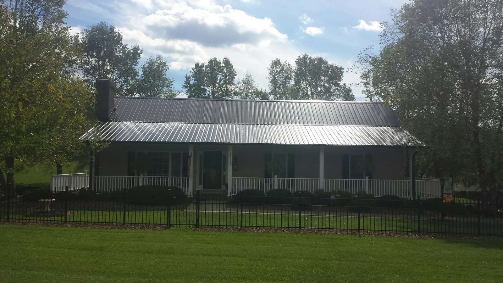 Gray metal roof on a brick ranch with a full width front porch — Gutter Guard Installation work by our crew in Hornbrook