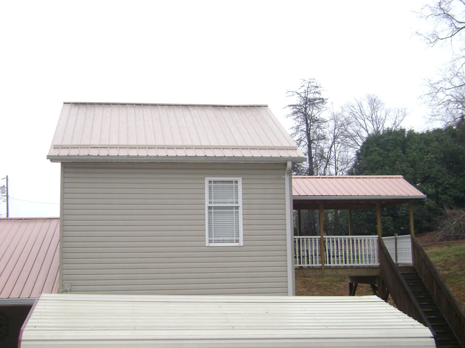 Tan metal roofs on a two story addition and attached porch, from a Roof Replacement job in Hornbrook