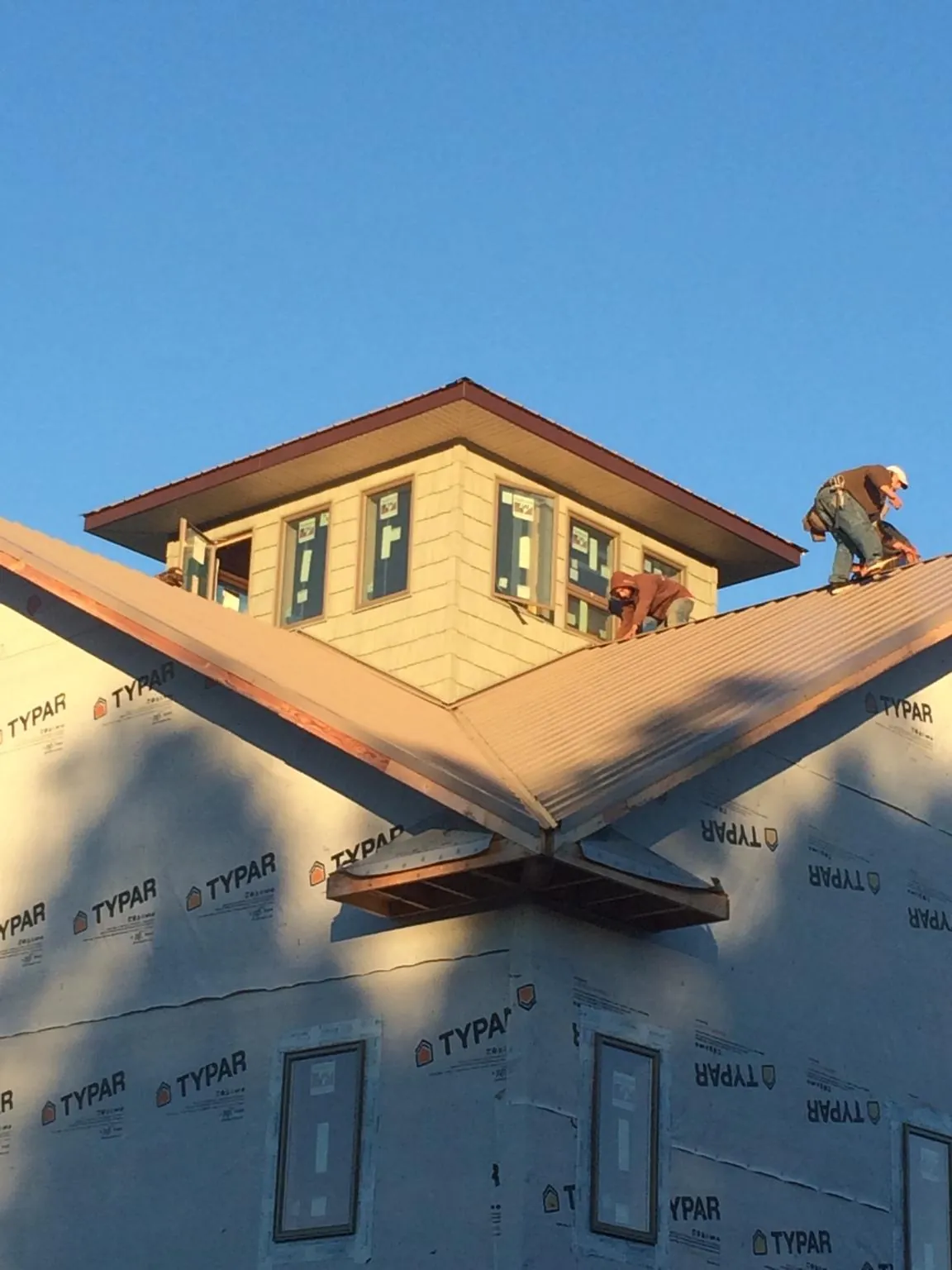 Roofers working around a rooftop cupola on a new metal roof at sunset — Roof Waterproofing in Hornbrook by Roofing Brothers